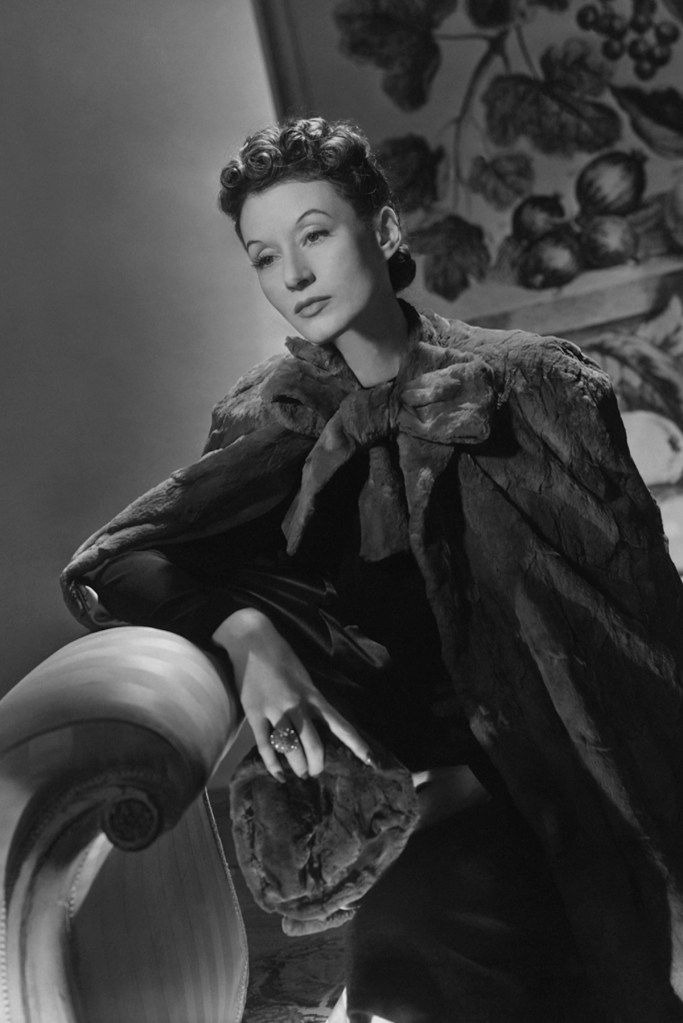 Circa January 1939 --- Millicent Rogers, hat in hand, wearing moleskin cape and large ring. She rests her arm on the back of a chaise lounge. --- Image by © Condé Nast Archive/Corbis